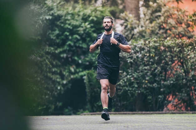 Un homme déterminé qui court dans le parc, un garçon en forme qui fait de l'exercice en plein air, un bel homme sportif.
