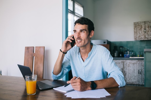 Homme déterminé utilisant des appareils et écrivant des notes à la maison