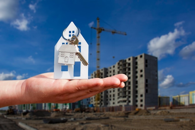 L'homme détient les clés de la maison dans ses mains dans le contexte d'un immeuble de plusieurs étages. Concept d'achat et de location d'appartements.