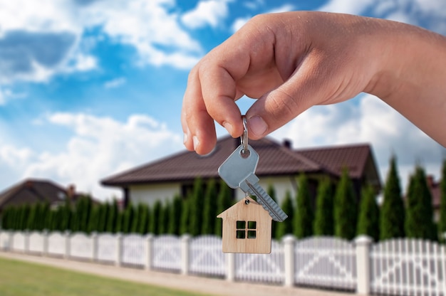 L'homme détient les clés de la maison dans ses mains sur fond de bâtiments résidentiels. Concept d'achat et de location d'appartements.