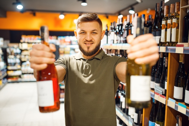 Homme avec deux bouteilles d'alcool en épicerie