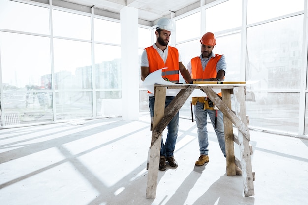 Homme de deux ingénieurs regardant le plan de projet sur la table dans le chantier de construction