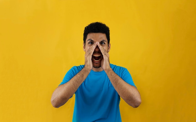 Homme disant un secret isolé sur fond jaune. Bel homme noir avec chemise bleue sur jaune.