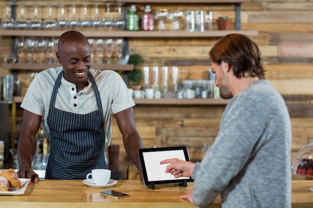 Homme discutant sur tablette numérique avec serveur