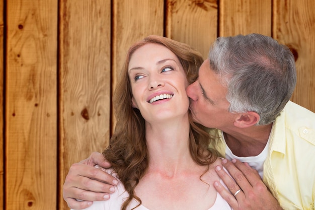 Photo homme donnant un baiser à son partenaire sur fond de bois