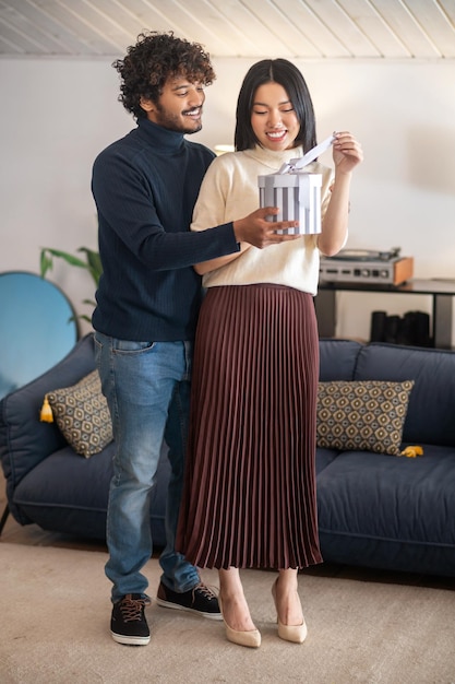 Homme donnant un cadeau à une femme souriante debout à l'intérieur