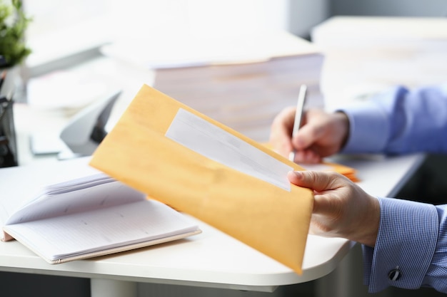 L'homme donne une enveloppe jaune au courrier pour une livraison ultérieure à l'adresse personnelle