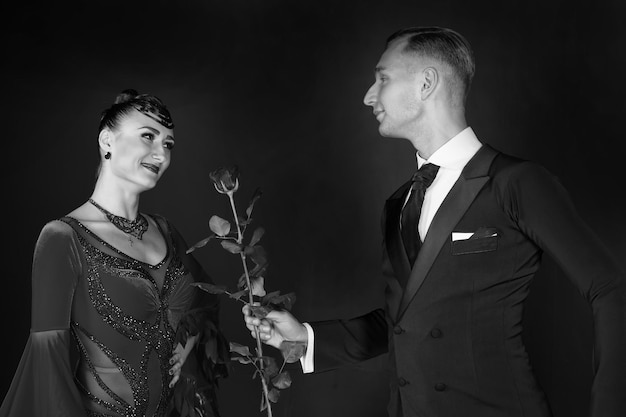 L'homme donne une fleur de rose à une femme heureuse en robe rouge