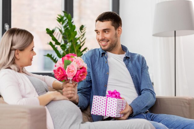 un homme donne des fleurs à une femme enceinte à la maison