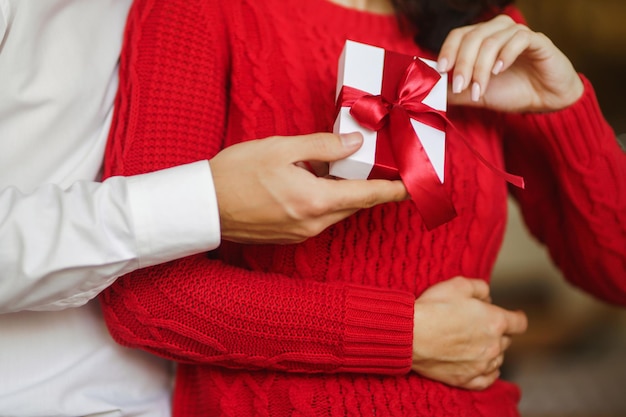 L'homme donne à sa femme une boîte-cadeau avec un ruban rouge Un couple d'amoureux célébrant la Saint-Valentin