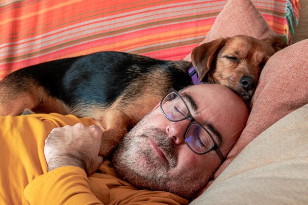 Homme dormant avec son chien sur le canapé