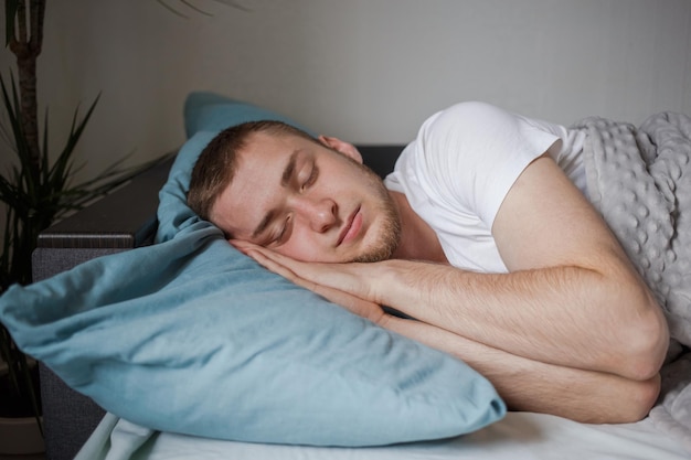 L'homme dort dans son lit avec ses mains sous sa tête