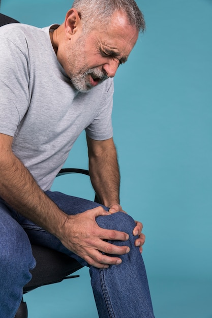 Photo homme avec douleur au genou assis sur une chaise