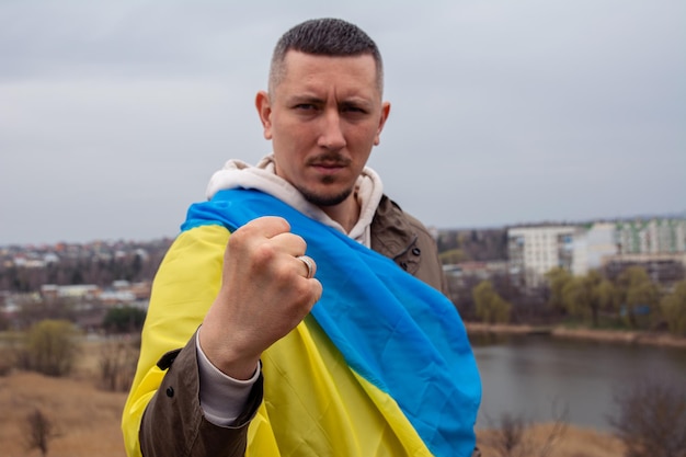 Un homme avec un drapeau de l'Ukraine dans le contexte d'une ville et d'un lac dans une ville ukrainienne