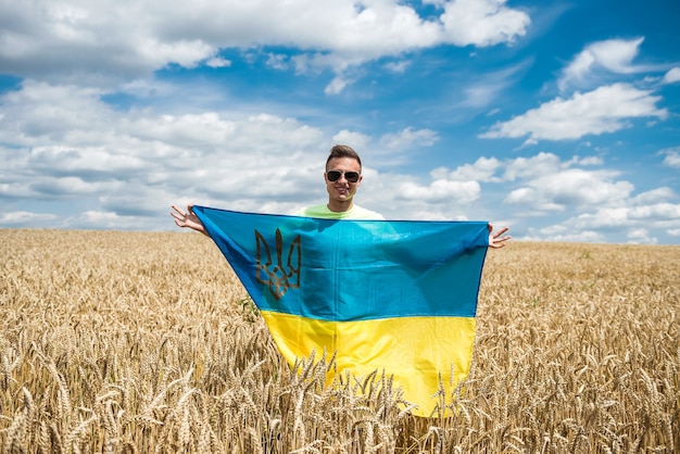 Homme avec drapeau ukrainien sur le champ de blé en été. mode de vie