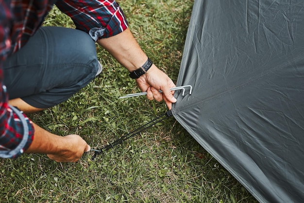 Photo un homme dresse une tente au camping pendant les vacances d'été, préparant le camping pour se reposer et se détendre.
