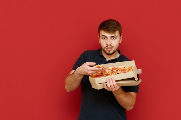 Photo homme drôle affamé se lève et prend une tranche de pizza hors de la boîte