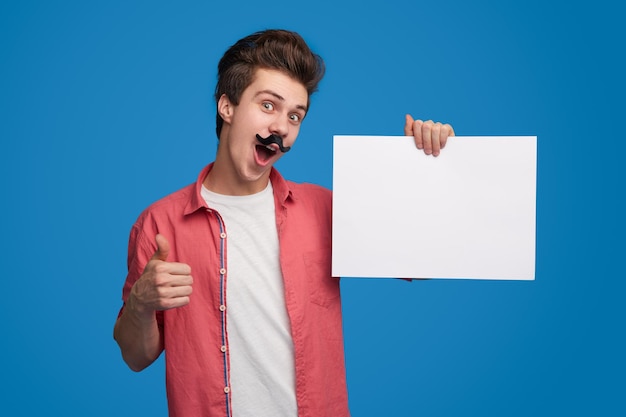 Homme drôle avec une feuille de papier vide montrant le pouce vers le haut