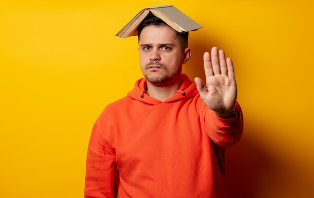 Homme drôle avec un livre sur la tête sur un mur jaune