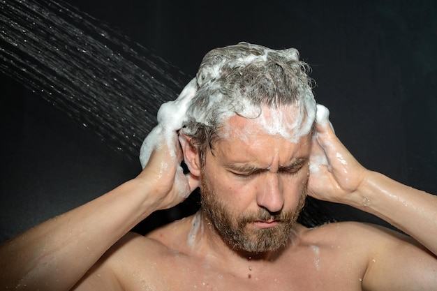 Homme du millénaire se lavant les cheveux, homme se baignant, tête de douche dans la baignoire, visage en mousse dans la douche, homme se baignant