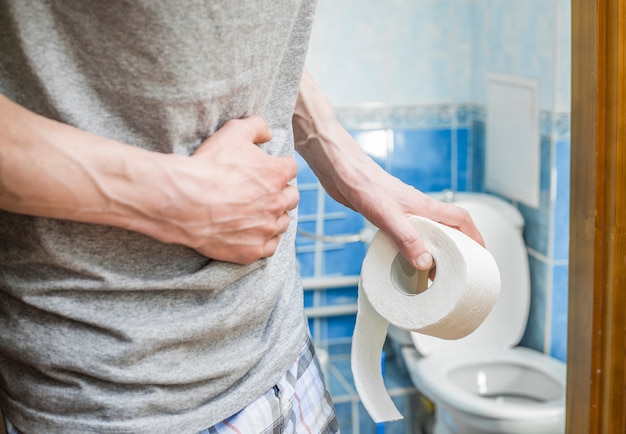 Un homme avec du papier hygiénique s'accroche à son ventre. La diarrhée.