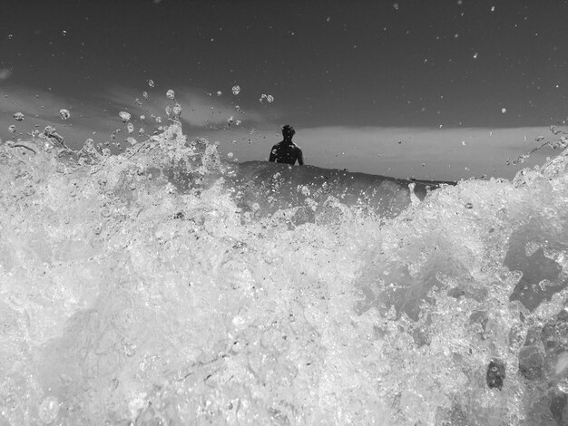 Photo un homme éclaboussant de l'eau dans la mer contre le ciel