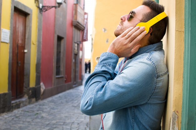 Homme écoutant de la musique avec des écouteurs jaunes dans la rue