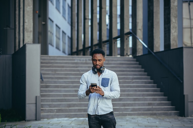 L'homme écoutant de la musique utilise de gros écouteurs, marche dans la rue, heureux afro-américain