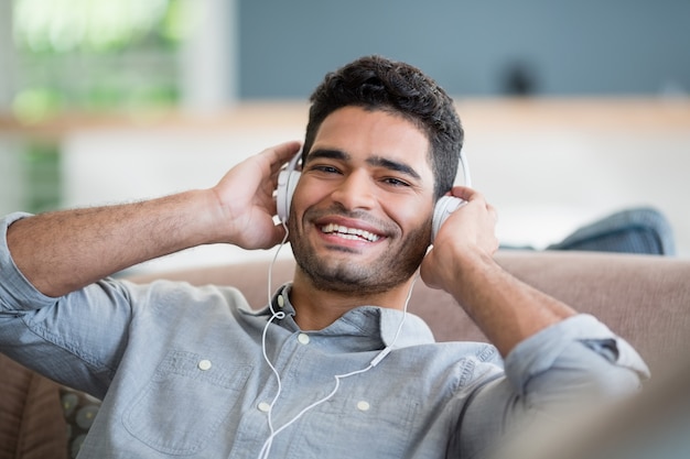 Homme, écouter musique, sur, écouteurs, dans, salle de séjour, chez soi