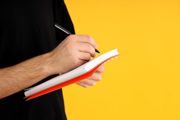 L'homme écrit dans un cahier sur fond jaune