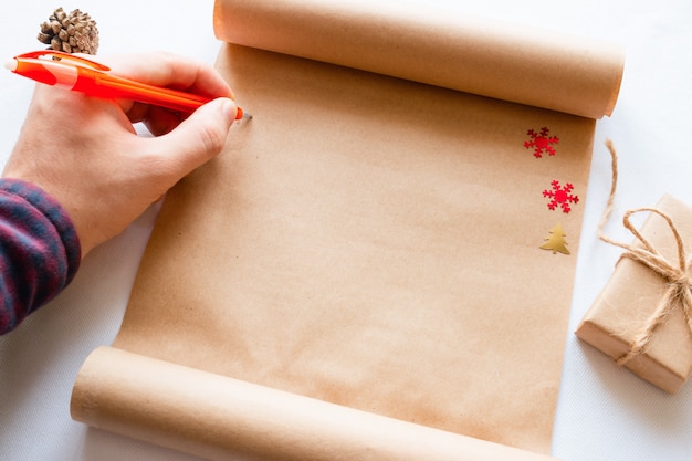 L'homme écrit dans le rouleau à côté d'un cadeau de Noël