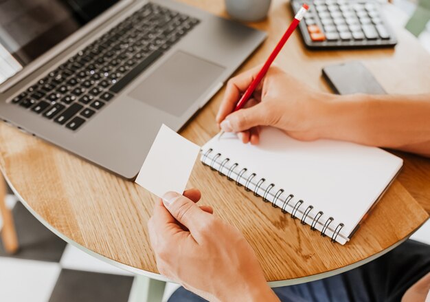 L'homme écrit des informations commerciales dans un ordinateur portable au lieu de travail au bureau avec pan coupé et ordinateur portable