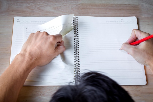 Photo un homme écrit à la main dans un cahier avec un crayon. des hommes pensent à quelque chose pendant qu'ils font leurs devoirs.