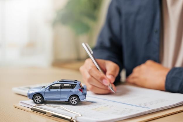Un homme écrit sa signature sur un contrat de financement ou de location de voiture idéal pour l'achat de véhicules, la location ou les accords de concession mettant l'accent sur les prêts automobiles