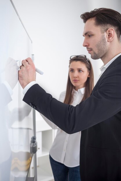 Photo homme écrivant au tableau blanc au bureau