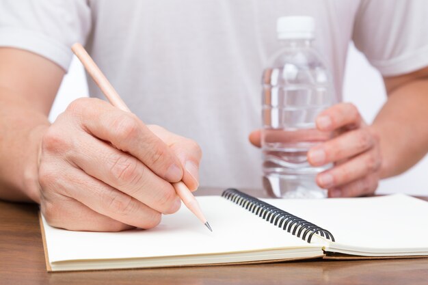 Homme écrivant sur ordinateur portable et tenant la bouteille d&#39;eau