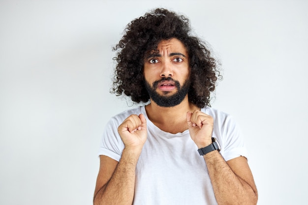 Un homme effrayé effrayé regarde la caméra, un gars d'apparence arabe en t-short blanc décontracté