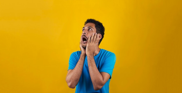 Homme effrayé isolé sur fond jaune. Bel homme noir avec chemise bleue sur jaune.