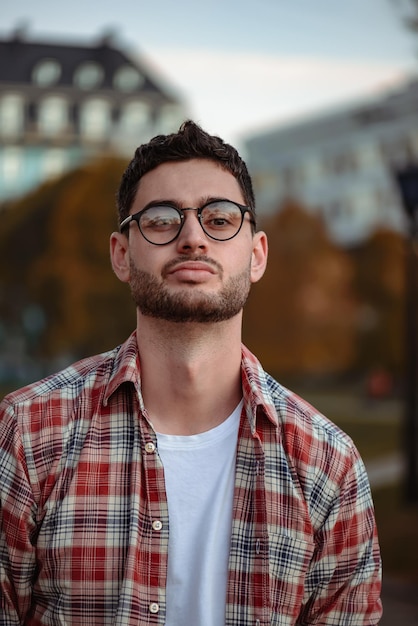 Homme élégant avec une barbe et des lunettes de soleil debout dans le parc.