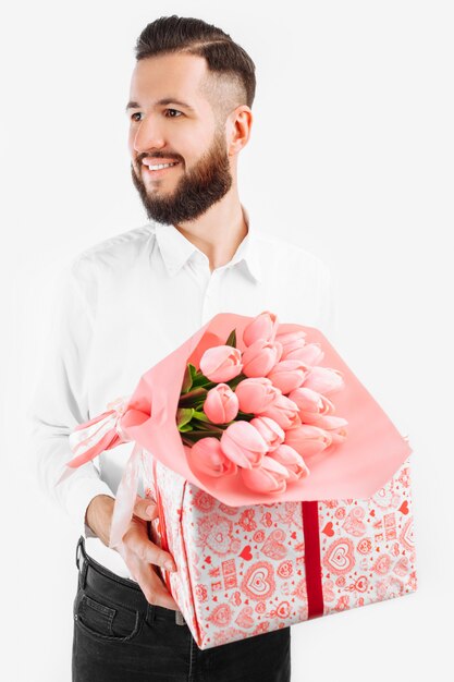 Homme élégant avec une barbe tenant un bouquet de tulipes et une boîte cadeau, un cadeau pour la Saint Valentin