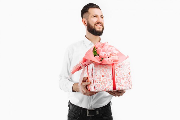 Homme élégant avec une barbe tenant un bouquet de tulipes et une boîte cadeau, un cadeau pour la Saint Valentin