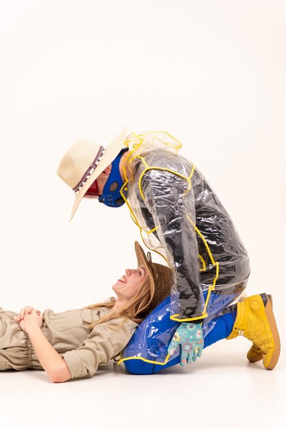 Homme élégant dans le masque et femme en chapeaux de paille posant sur fond blanc