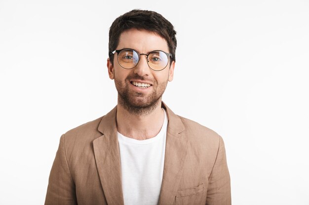 homme élégant avec du chaume portant une veste et des lunettes souriant à l'avant isolé sur un mur blanc