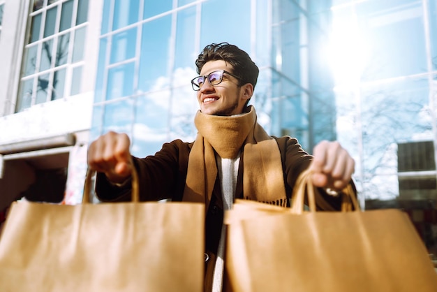 Homme élégant avec des emballages en papier après le shopping Vente concept de style de vie consumériste