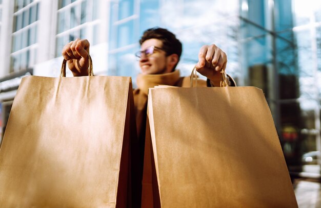 Homme élégant avec des emballages en papier après le shopping Vente concept de style de vie consumériste