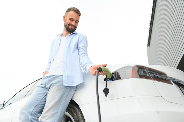 Un homme élégant insère une fiche dans la prise de charge de la voiture électrique