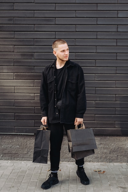 Homme élégant en noir avec des sacs shopping vendredi noir