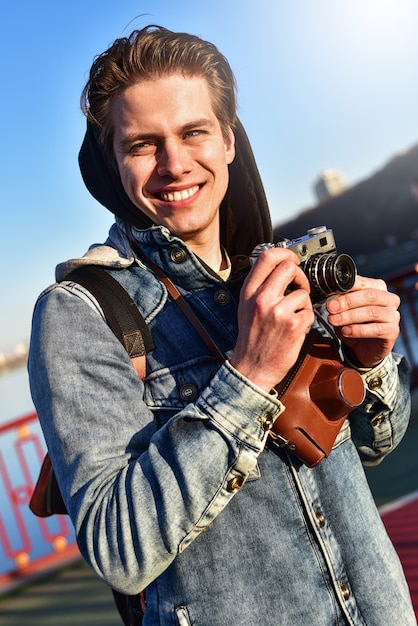 Homme élégant photographiant sur appareil photo rétro. Séjour touristique sur le pont et faire une photo.