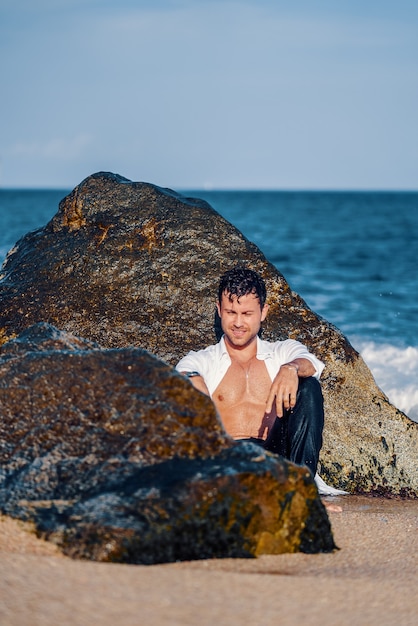 Homme élégant souriant sur la côte rocheuse