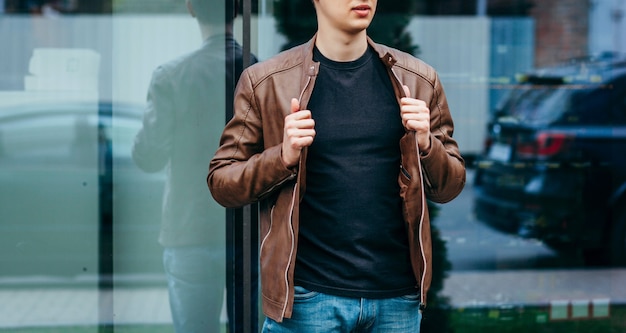 Un homme élégant en veste de cuir, lunettes et t-shirt noir. Photo de rue